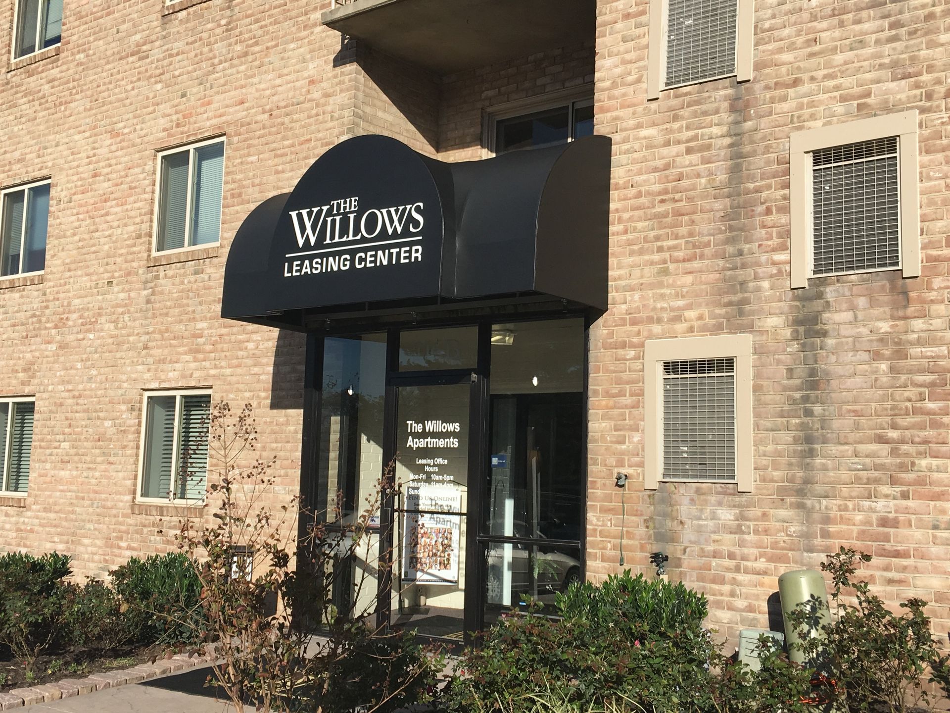 A brick building with a black awning over the entrance.