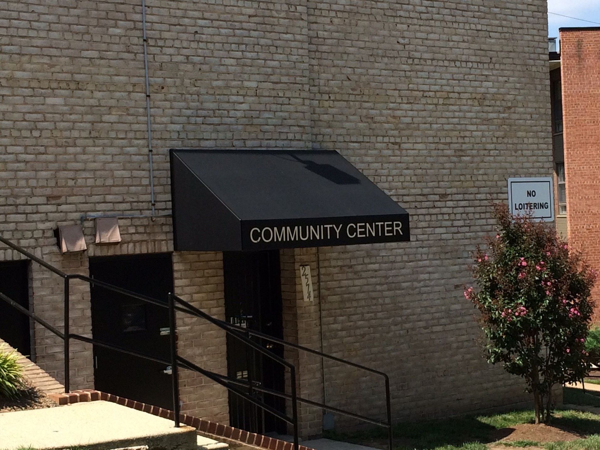 A brick building with a black awning that says community center