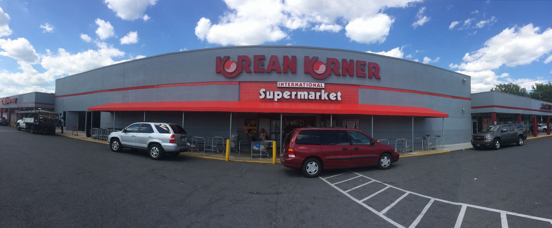 A red van is parked in front of a korean corner supermarket.
