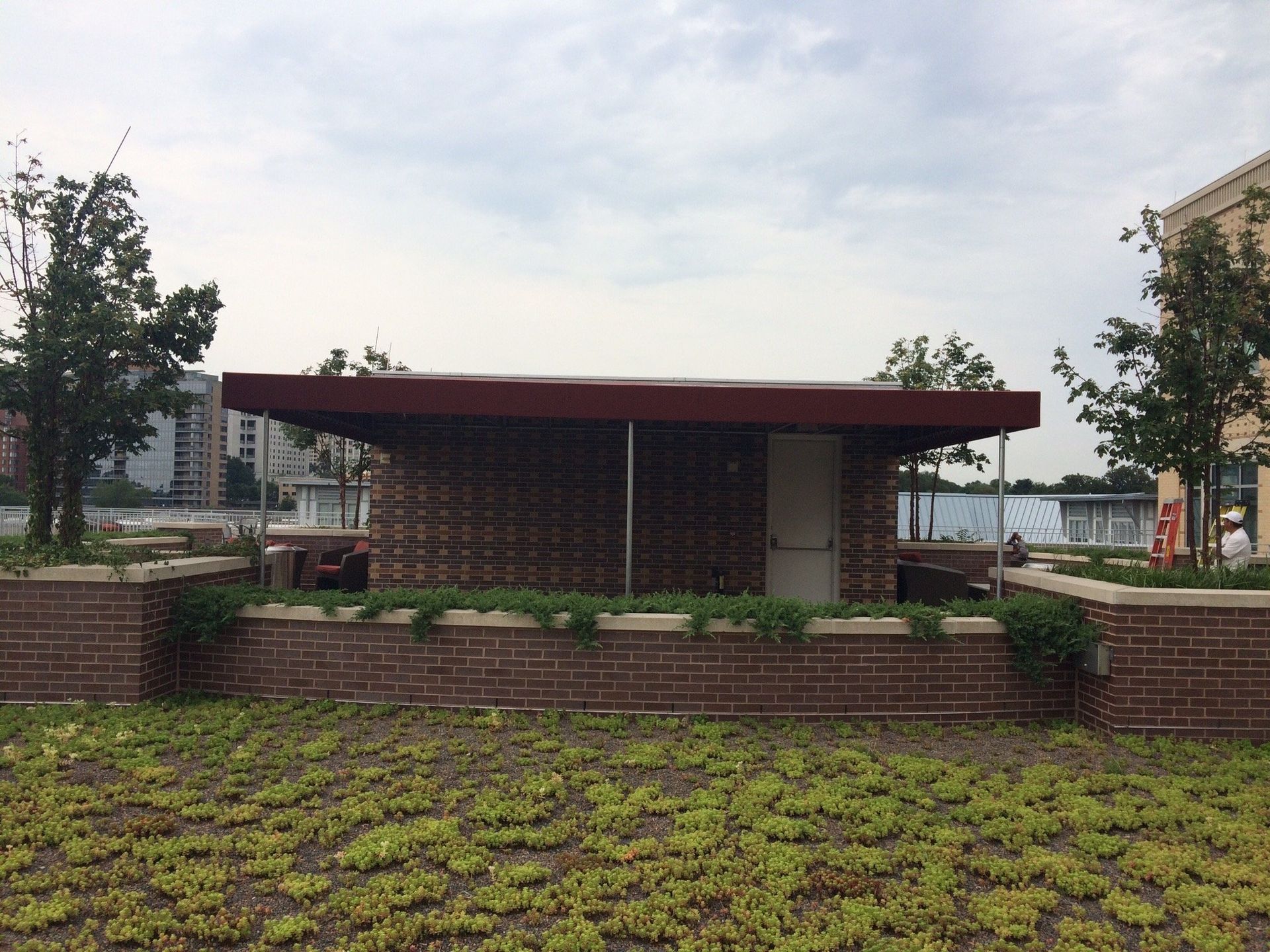 A brick building with a red roof is surrounded by a lush green field.