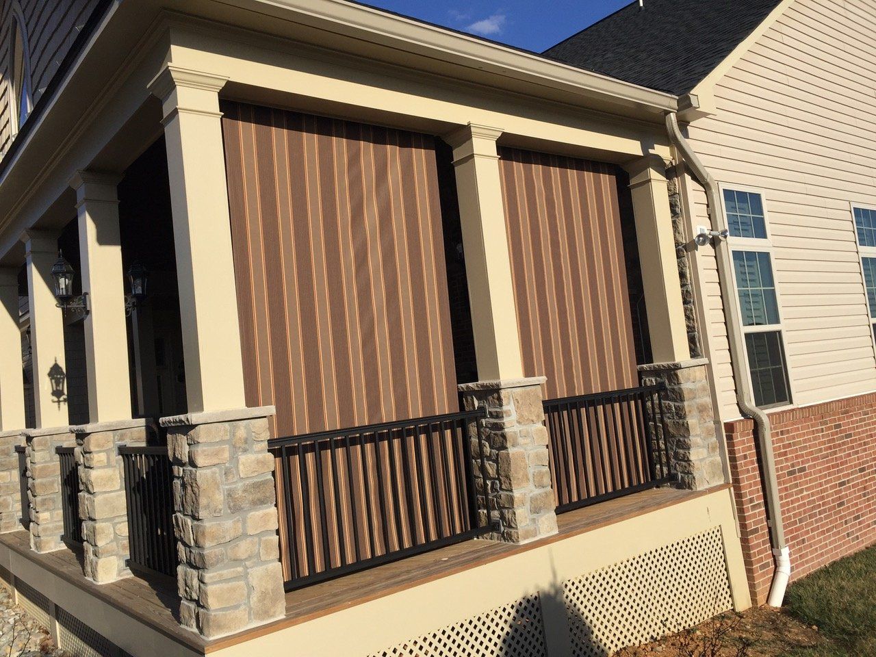 A house with a porch with striped blinds on it