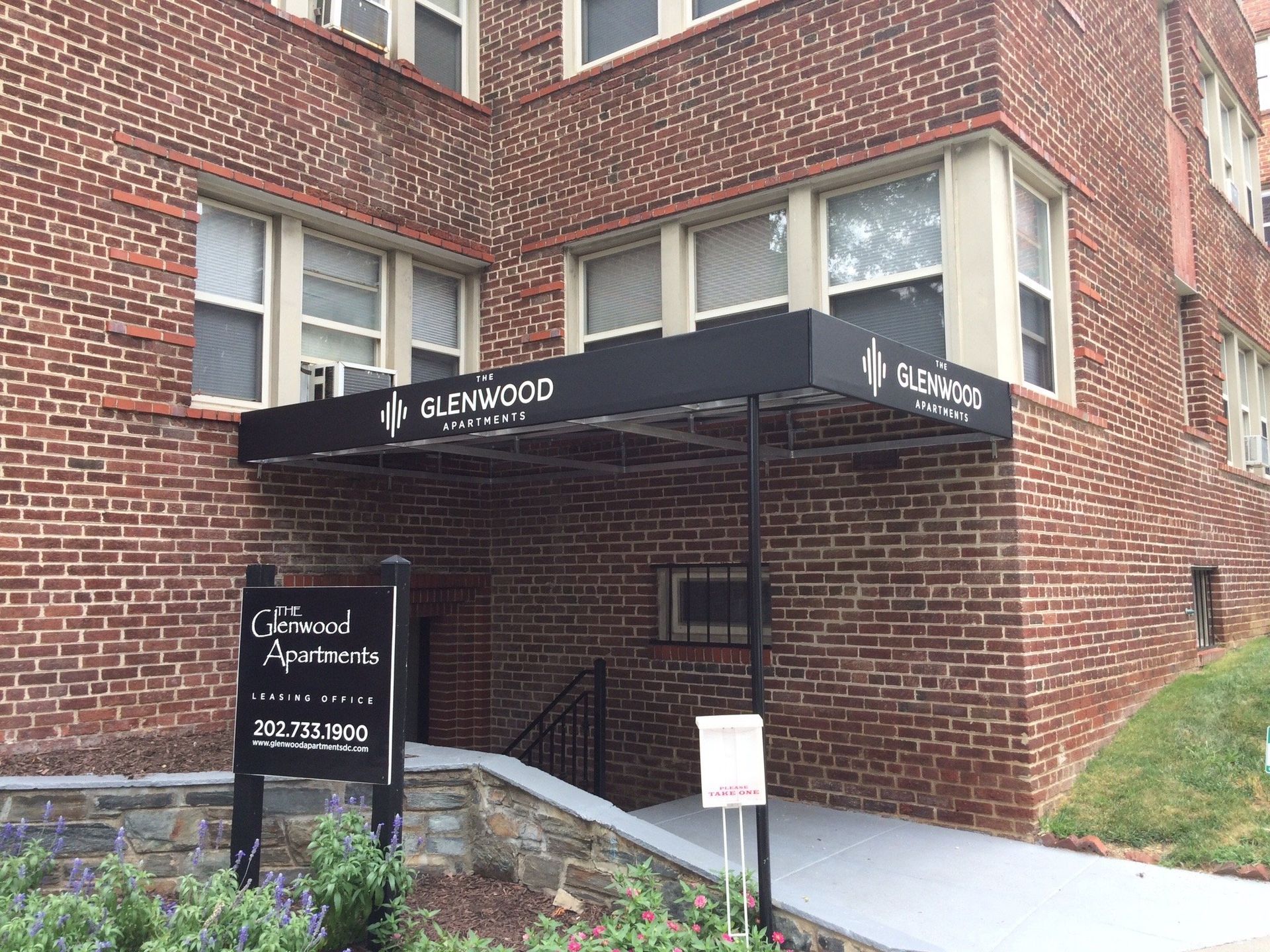 A brick building with a black awning over the entrance.