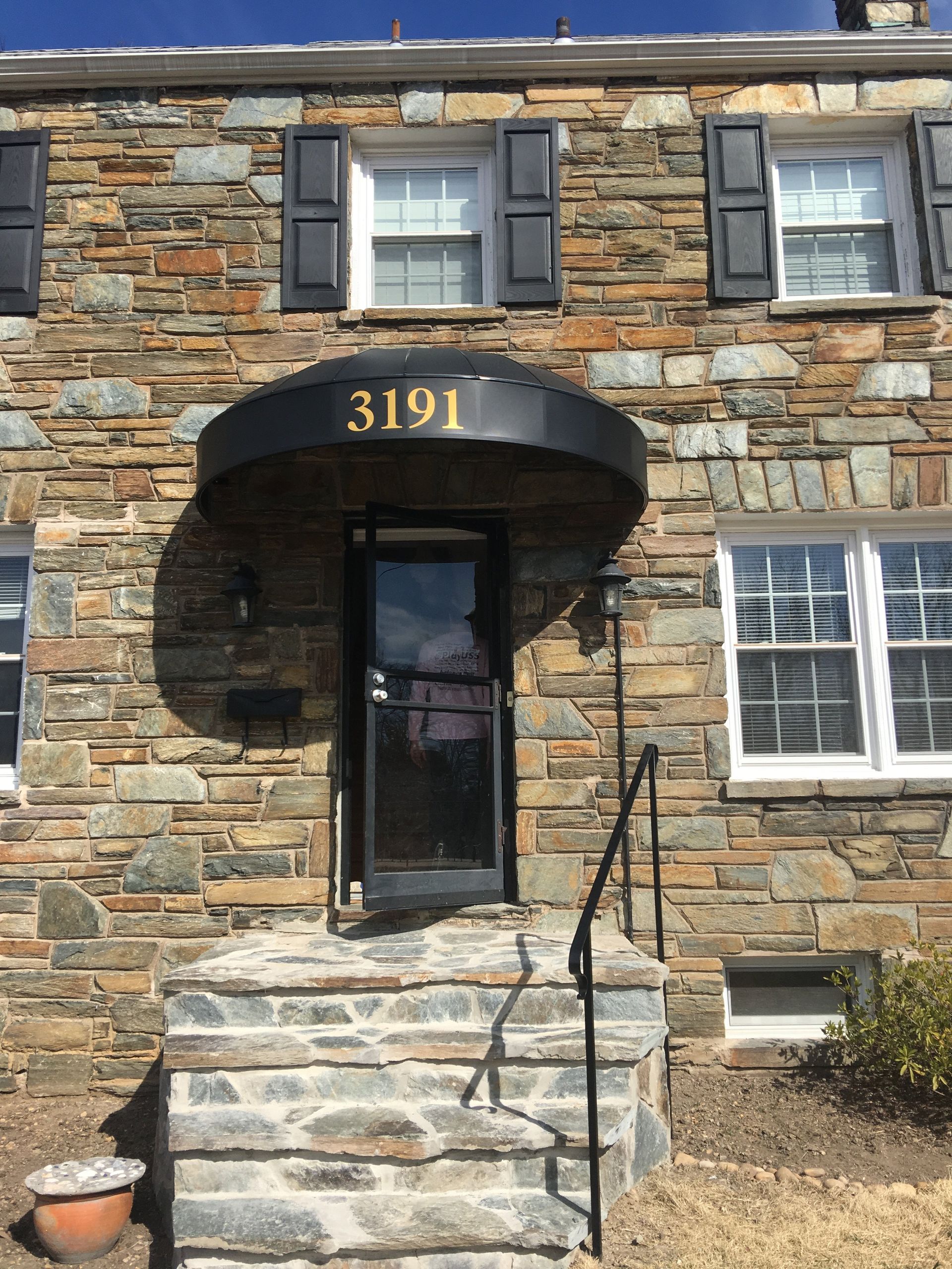 A stone building with a black awning the number  3191