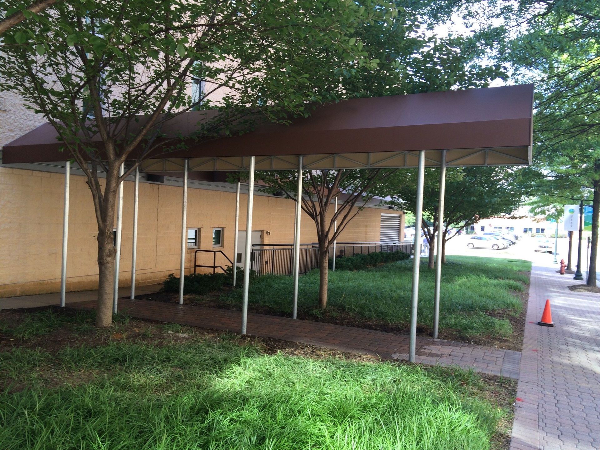 A covered walkway with trees and a building in the background