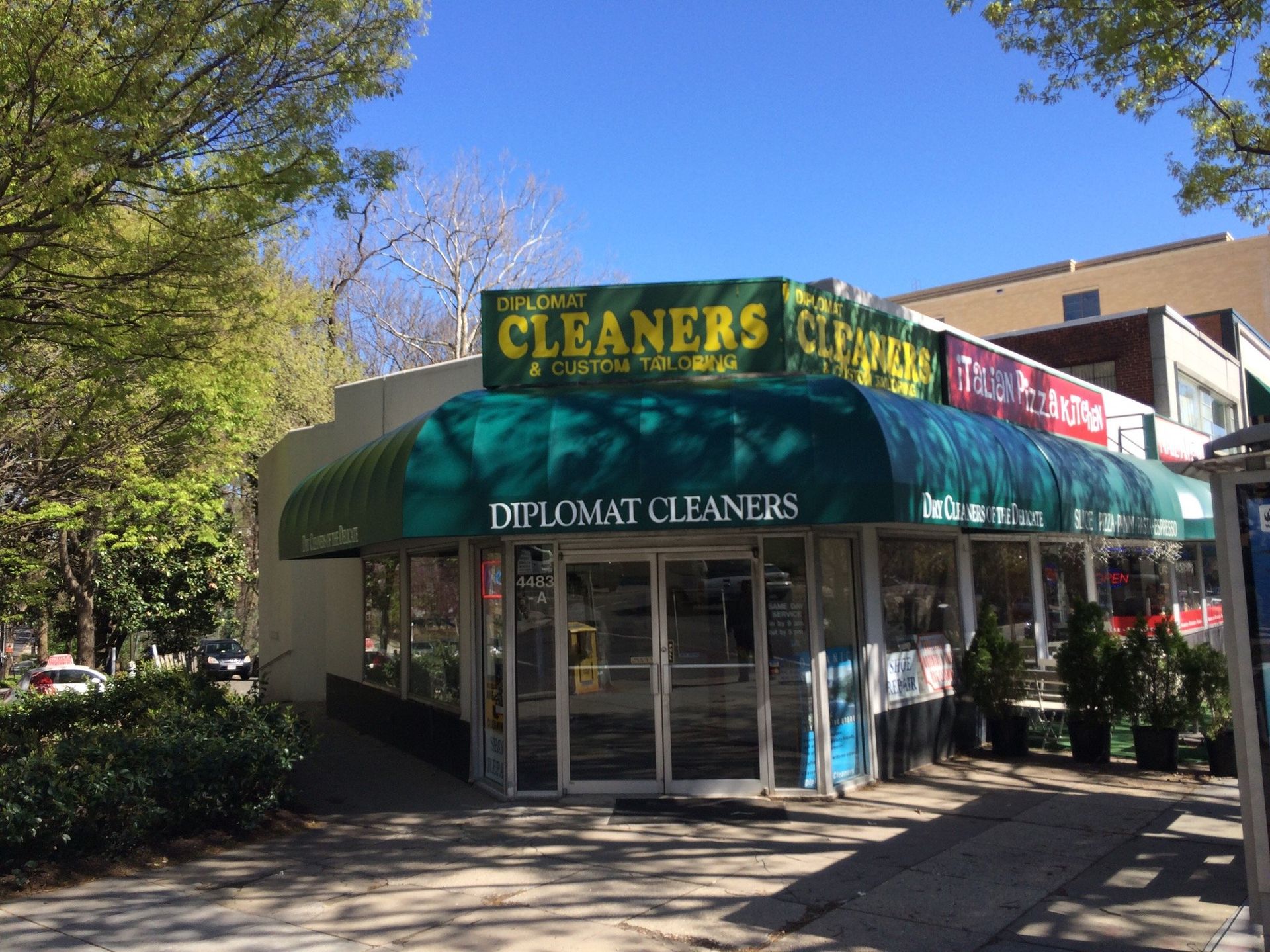 A building with a green awning that says cleaners on it