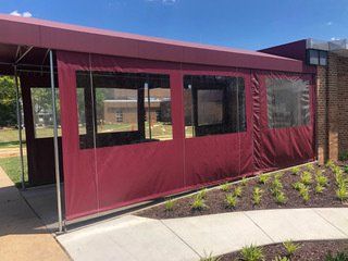 A red awning is covering the windows of a building