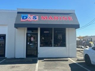A white building with a gray awning and a car parked in front of it