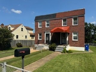 A brick house with a red awning and a mailbox in front of it