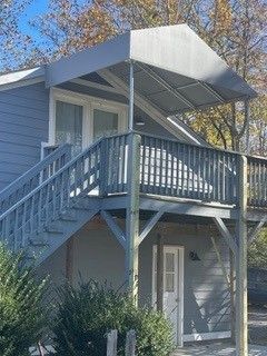 A small house with a deck and stairs leading up to it