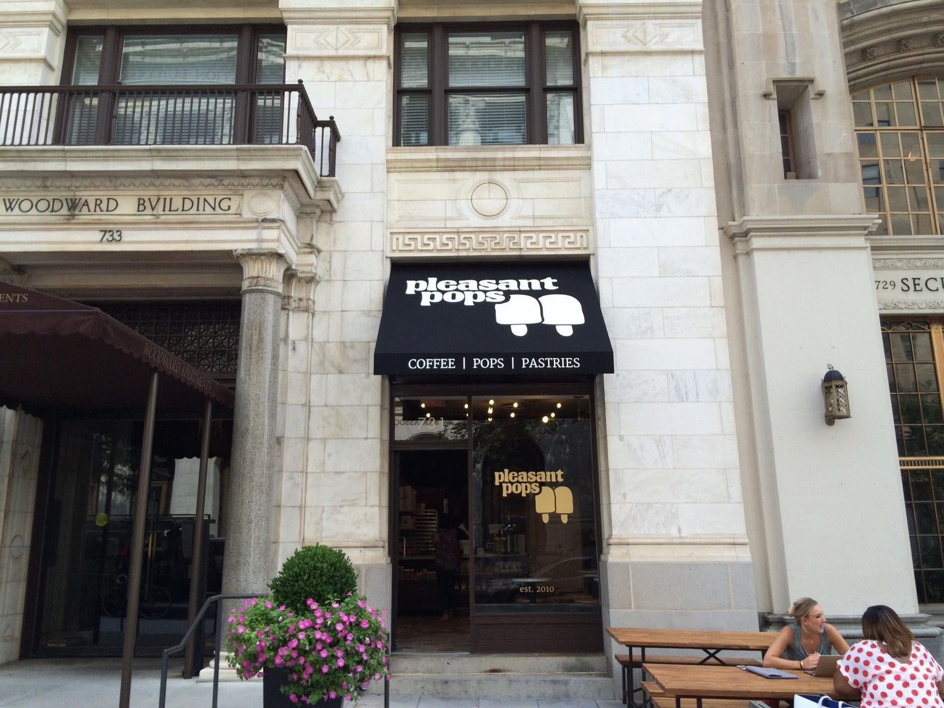 A group of people are sitting at tables outside of a restaurant.