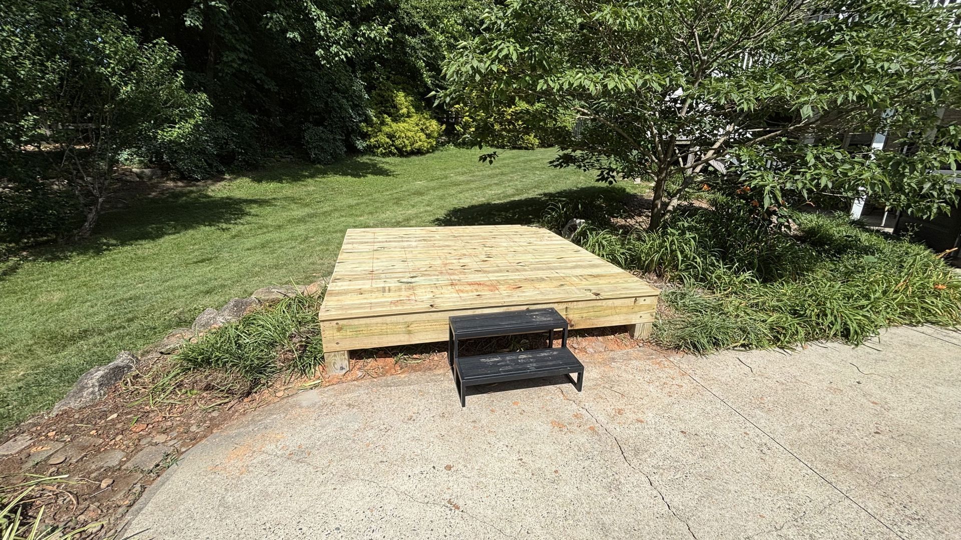 A wooden deck with stairs leading up to it in a yard.