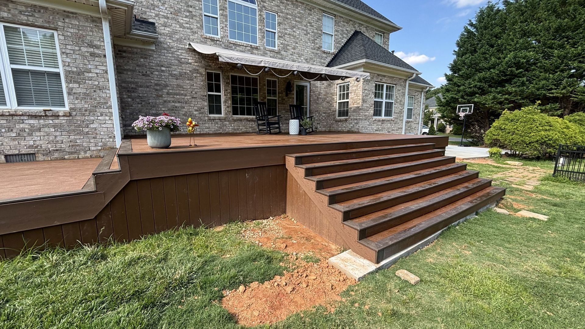 A large brick house with a wooden deck and stairs in front of it.