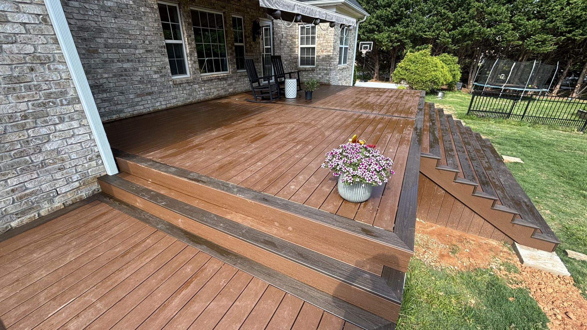 A wooden deck with stairs leading up to it in front of a brick house.