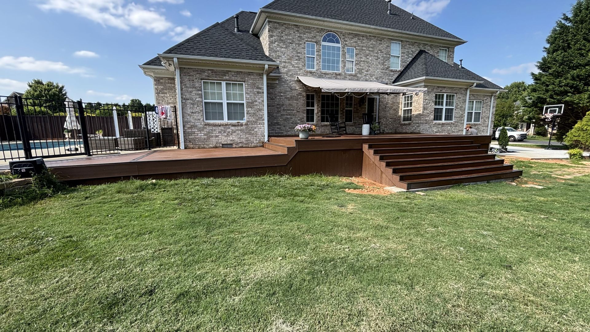 A large brick house with a large deck and stairs in the backyard.