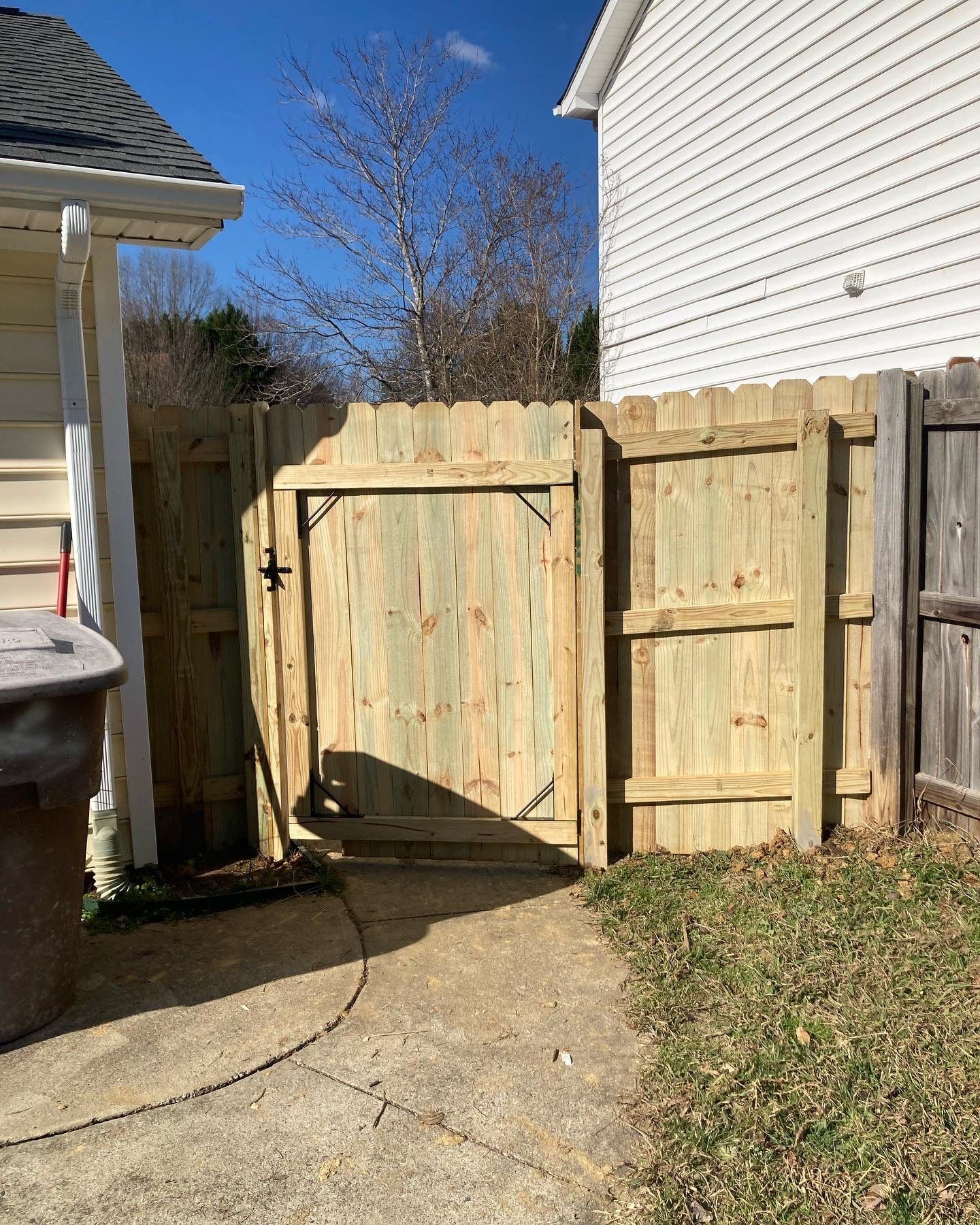 A wooden fence with a gate in the backyard of a house.