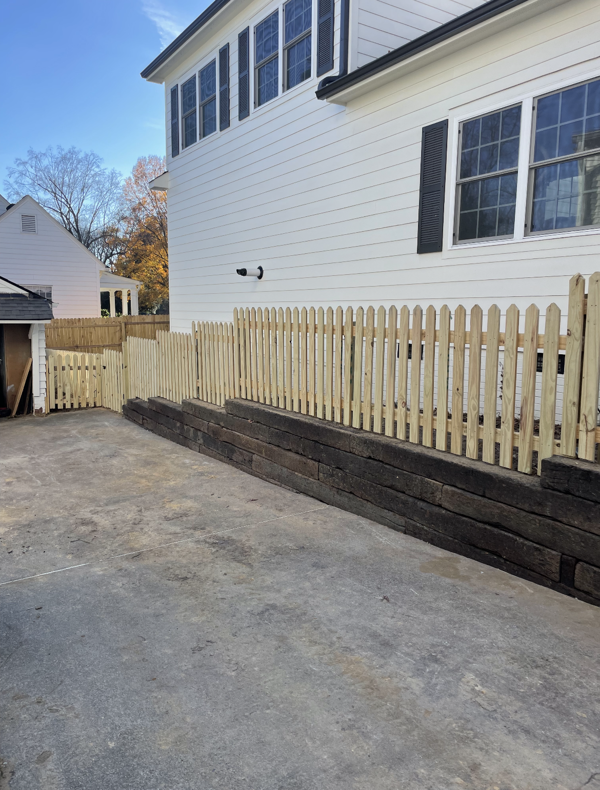 A white house with a wooden picket fence in front of it.