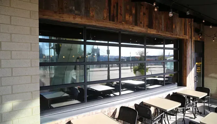 Empty café seating by a large window with outdoor view and wooden ceiling beams