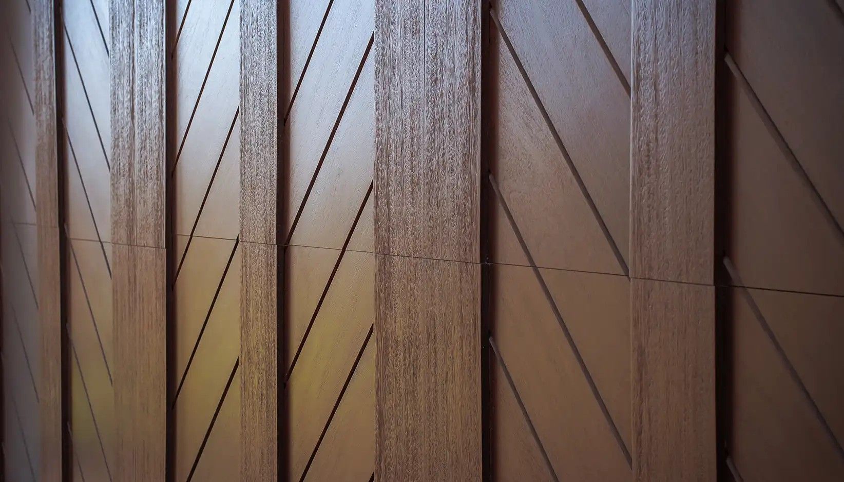 Brown wooden wall panels featuring a repeating geometric pattern of diagonal slats and vertical beams.
