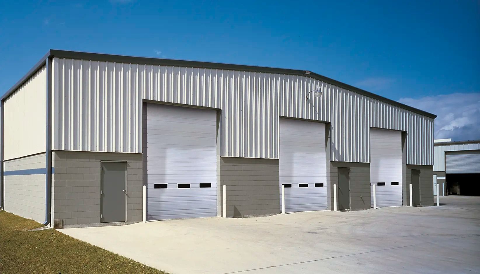 Large metal warehouse with multiple garage doors under a blue sky