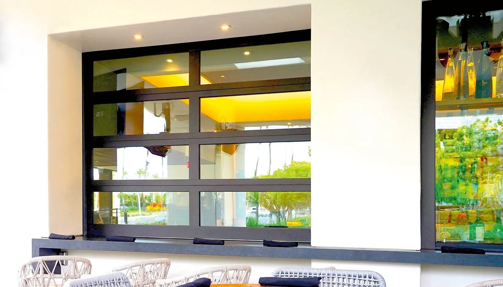 Modern interior with a large black-framed window, white walls, and colorful wall art.