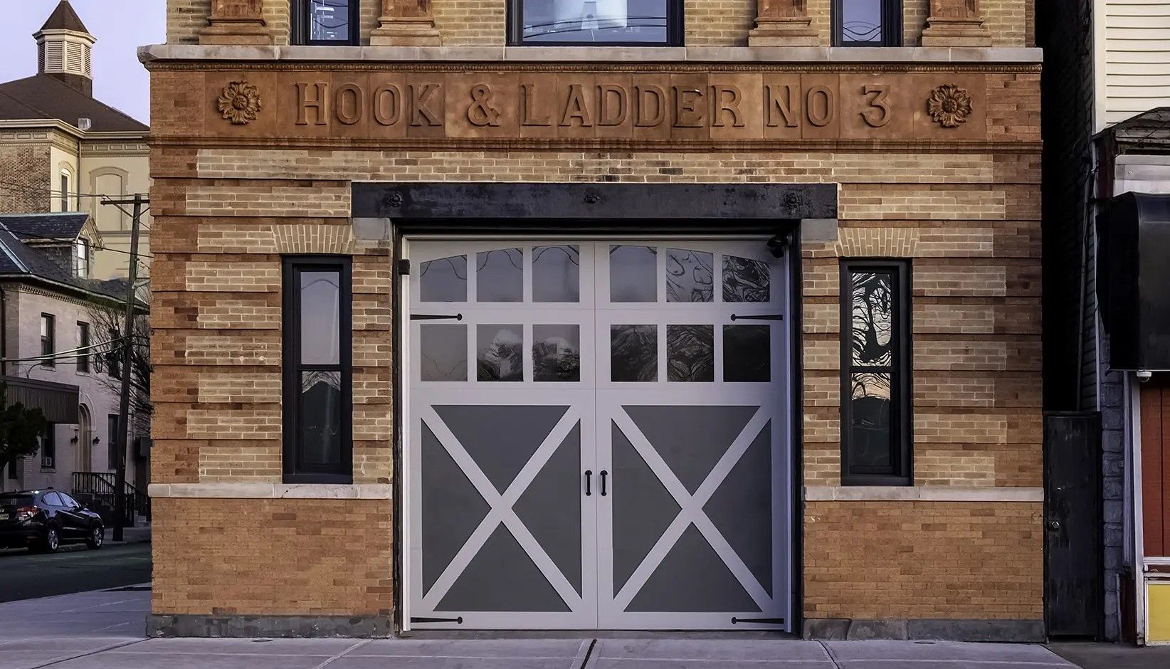 The brick facade of Hook & Ladder No. 3 fire station with a large, central white carriage-style garage door.
