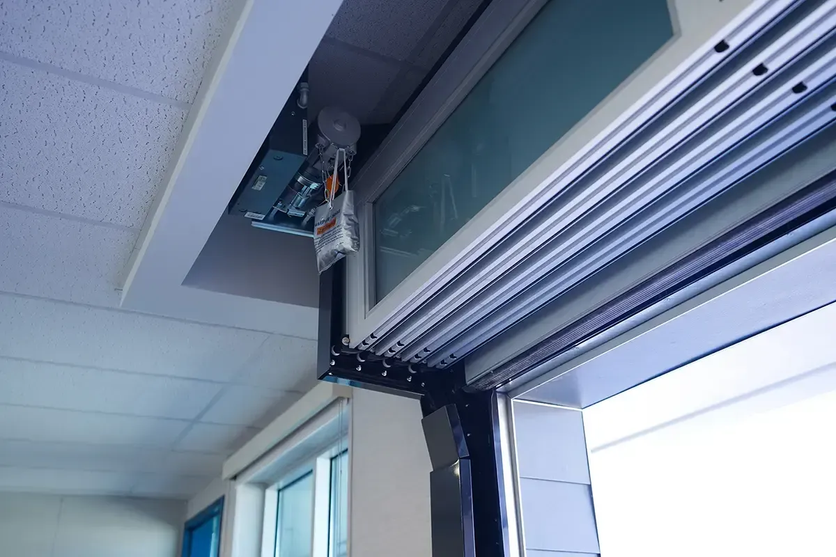 Open garage door track and motor near a ceiling with fluorescent lights