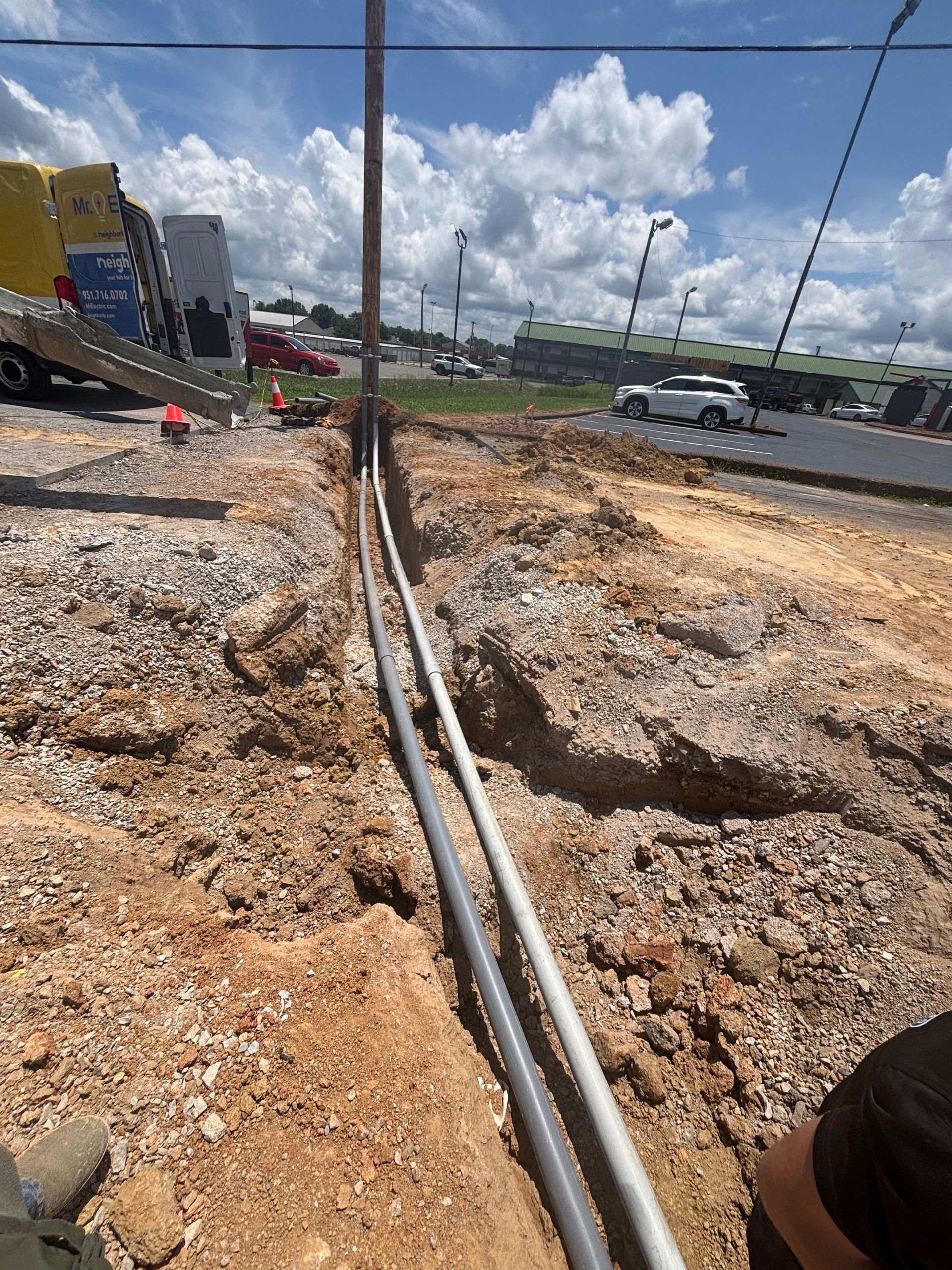 A person is standing in the dirt next to a pipe.