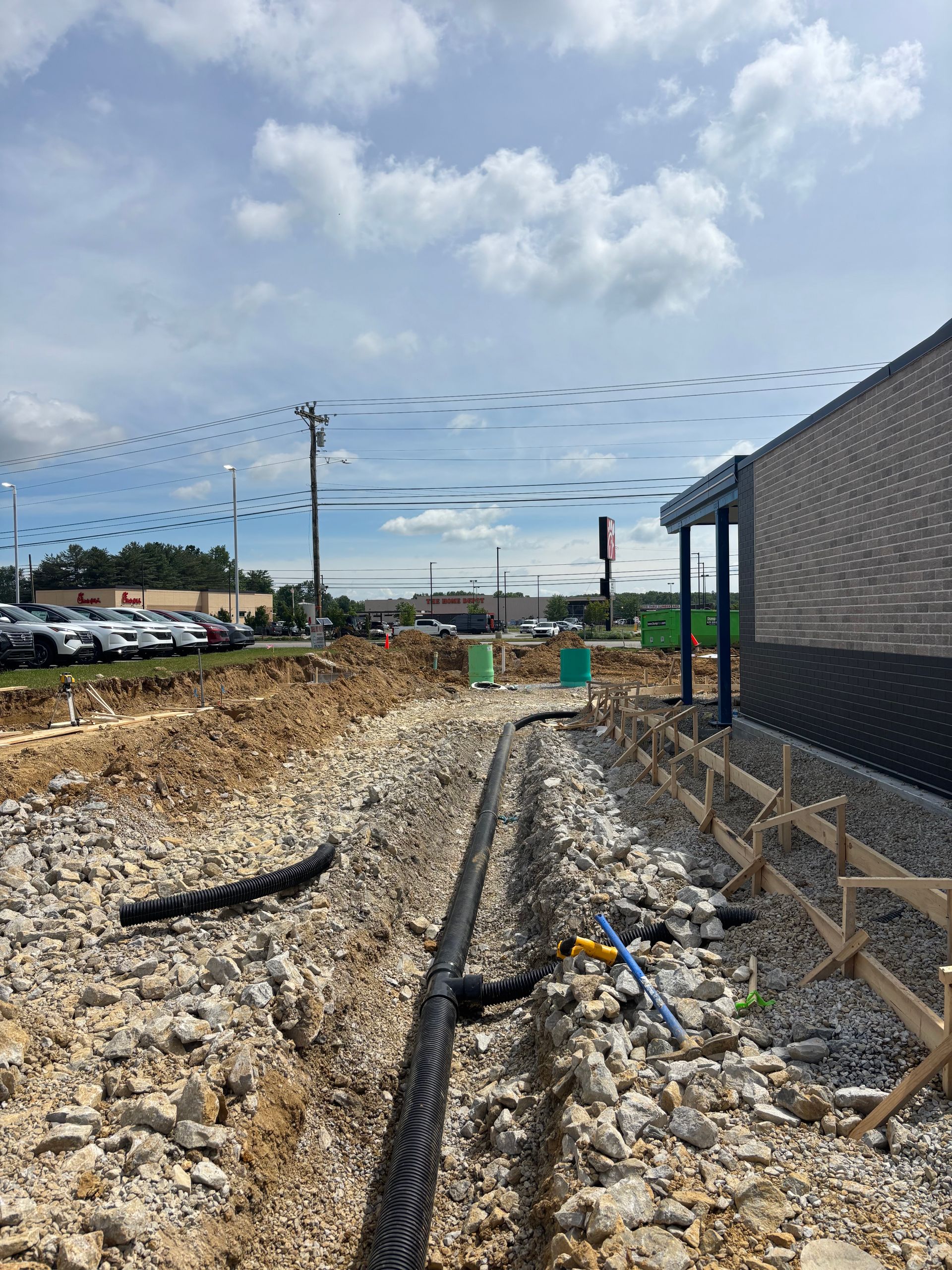 A construction site with a lot of rocks and a building in the background.