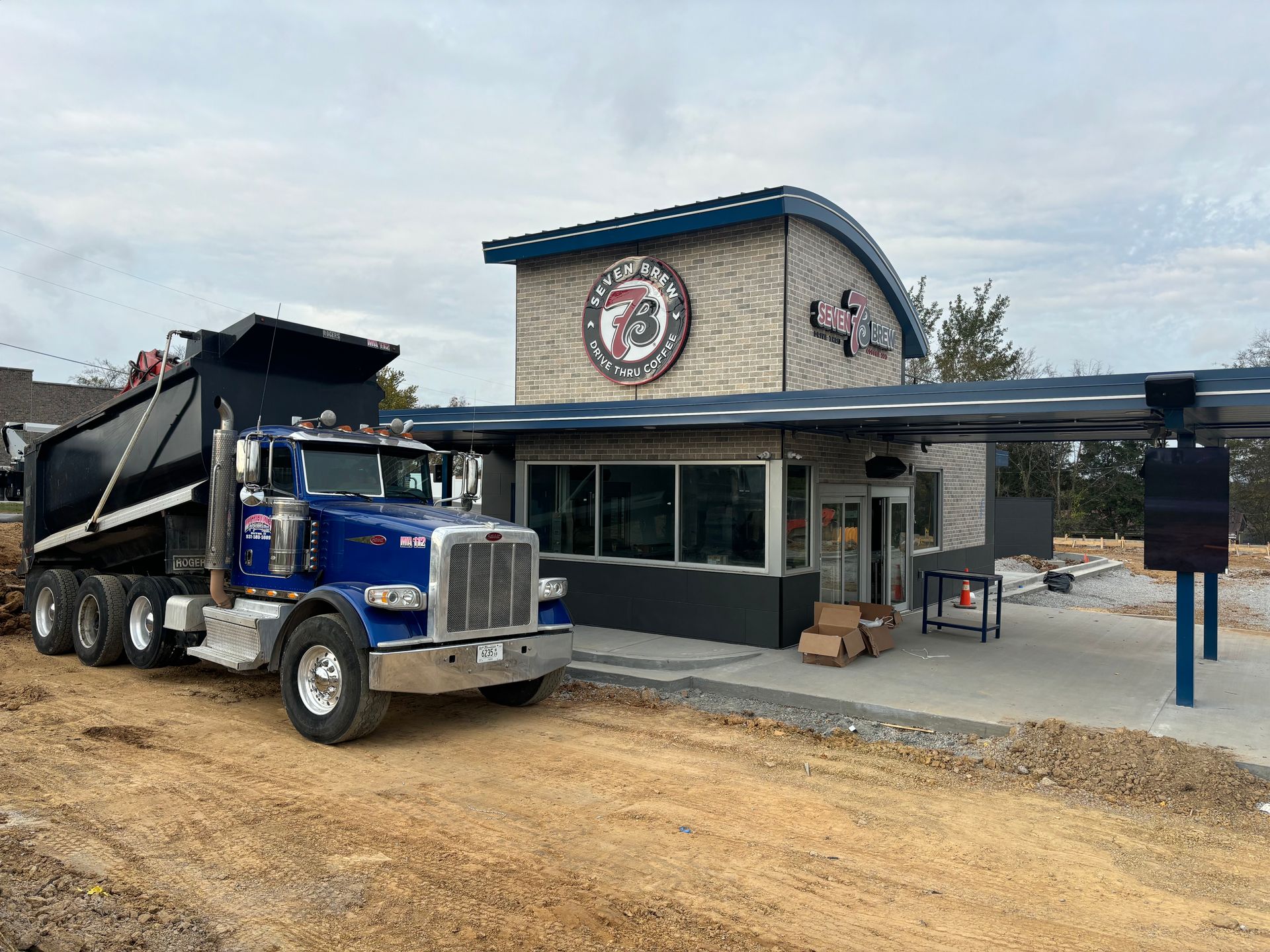 A dump truck is parked in front of a building under construction.