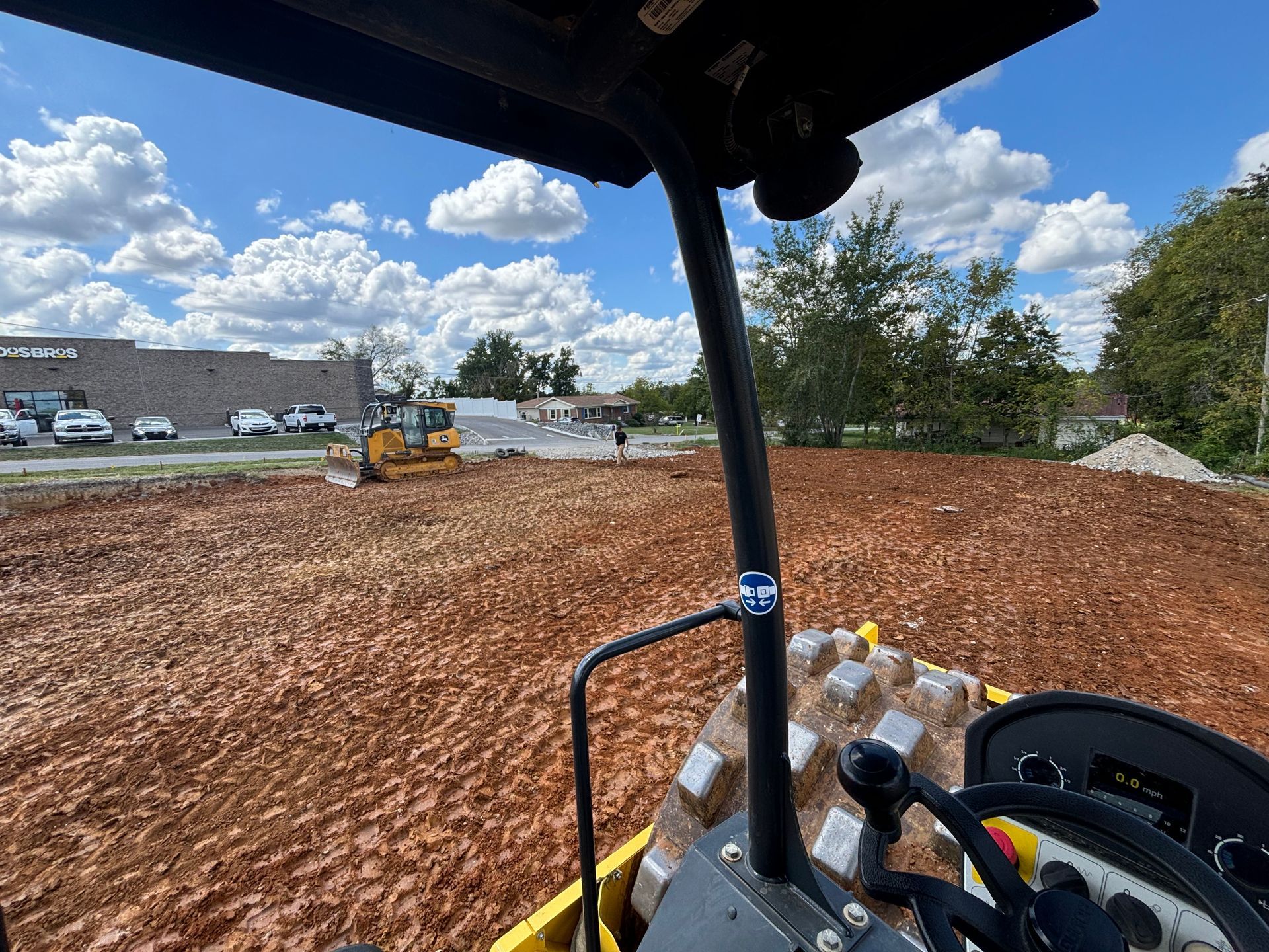 A person is driving a bulldozer through a dirt field.