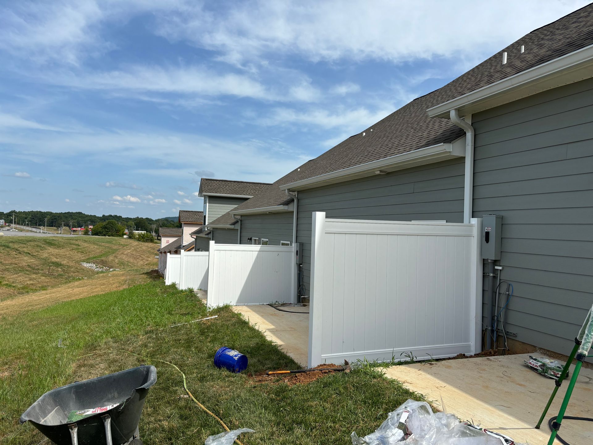 A white fence is being installed in front of a house.