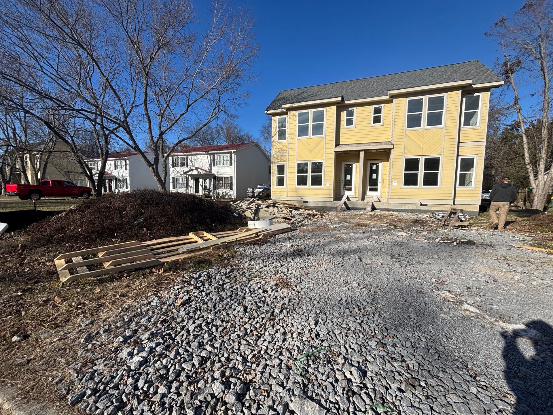 A yellow house is being built in a gravel lot.