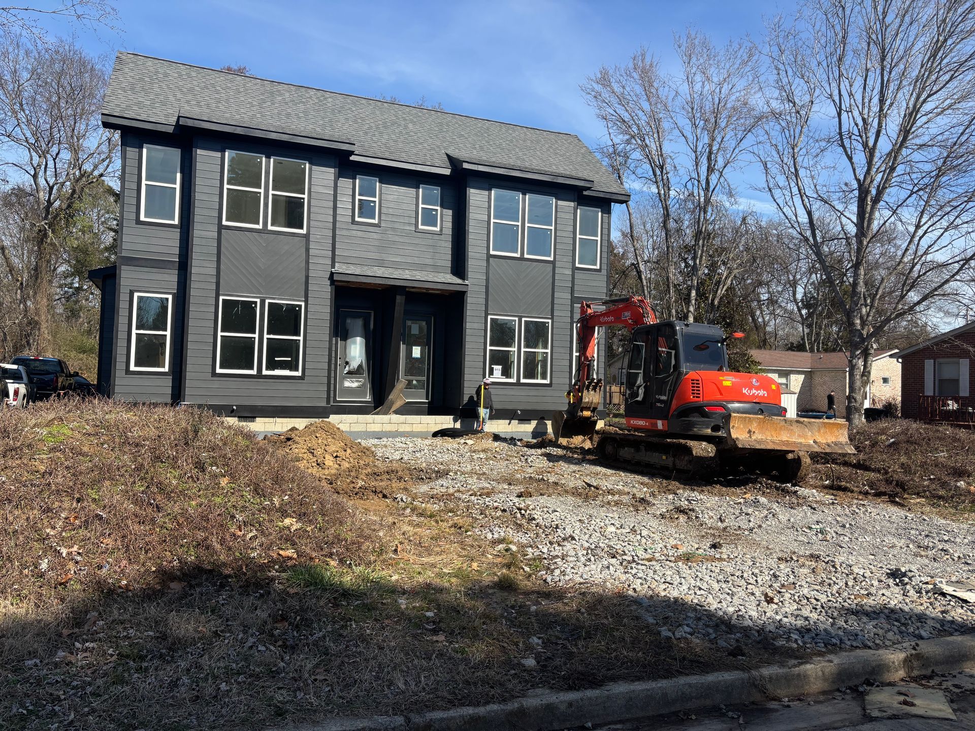A construction vehicle is parked in front of a house under construction.