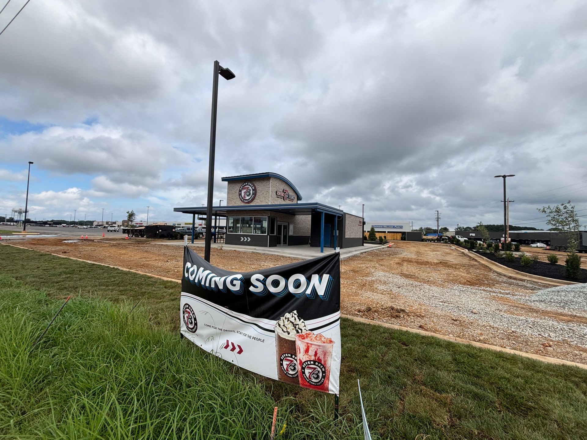 A sign that says coming soon is in front of a building under construction.