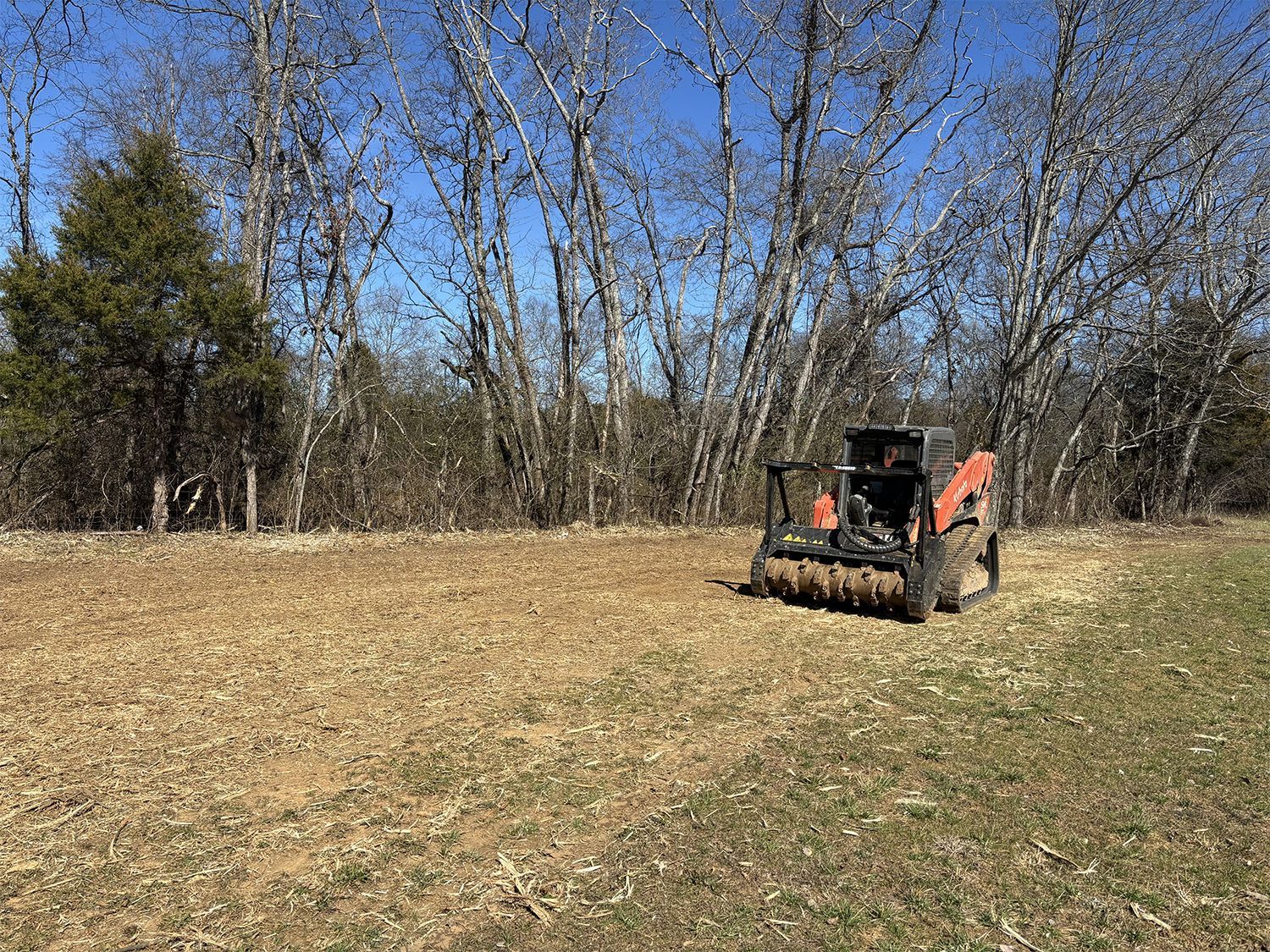 A tractor is sitting in a field with trees in the background.