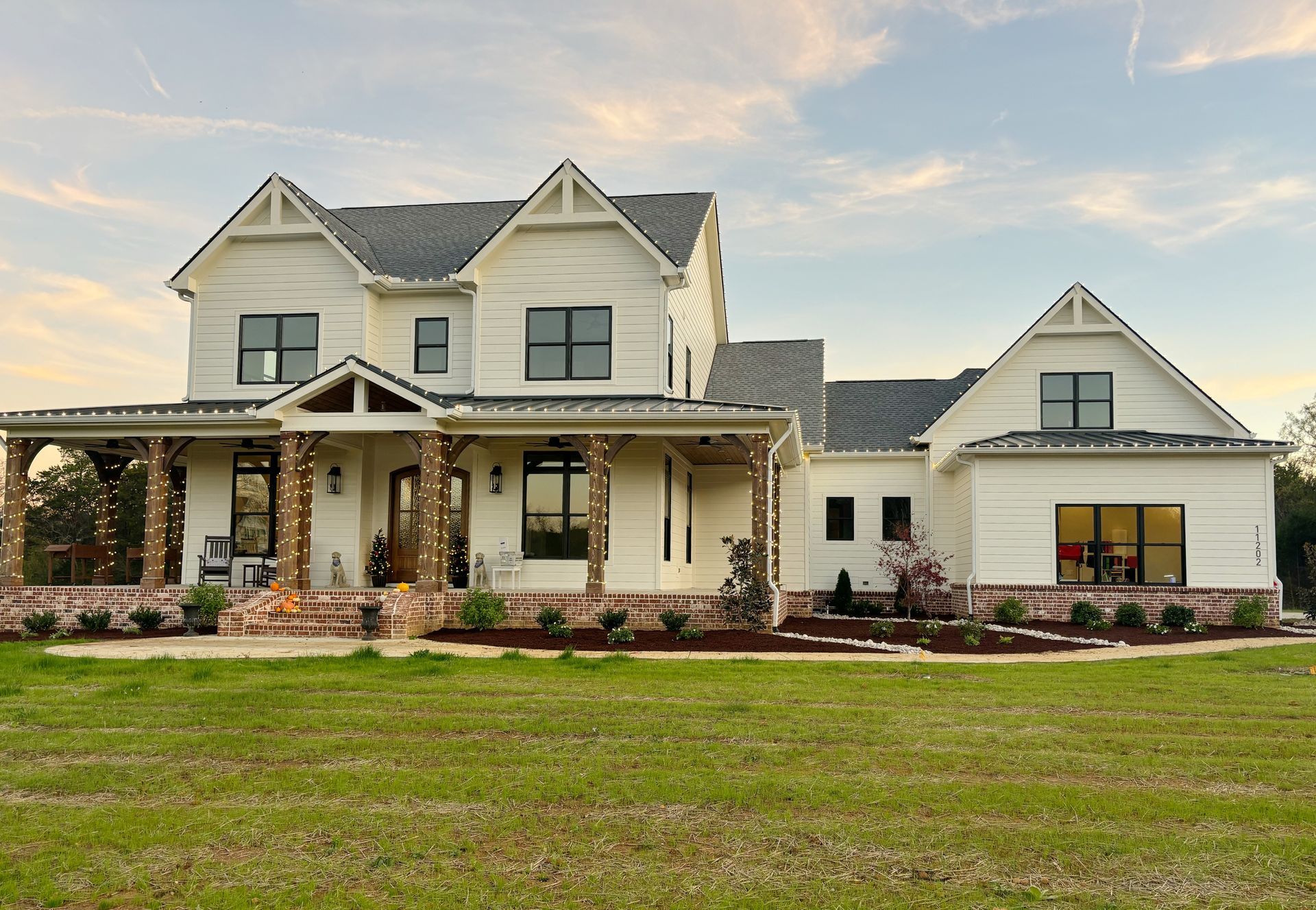A large white house is sitting on top of a lush green field.