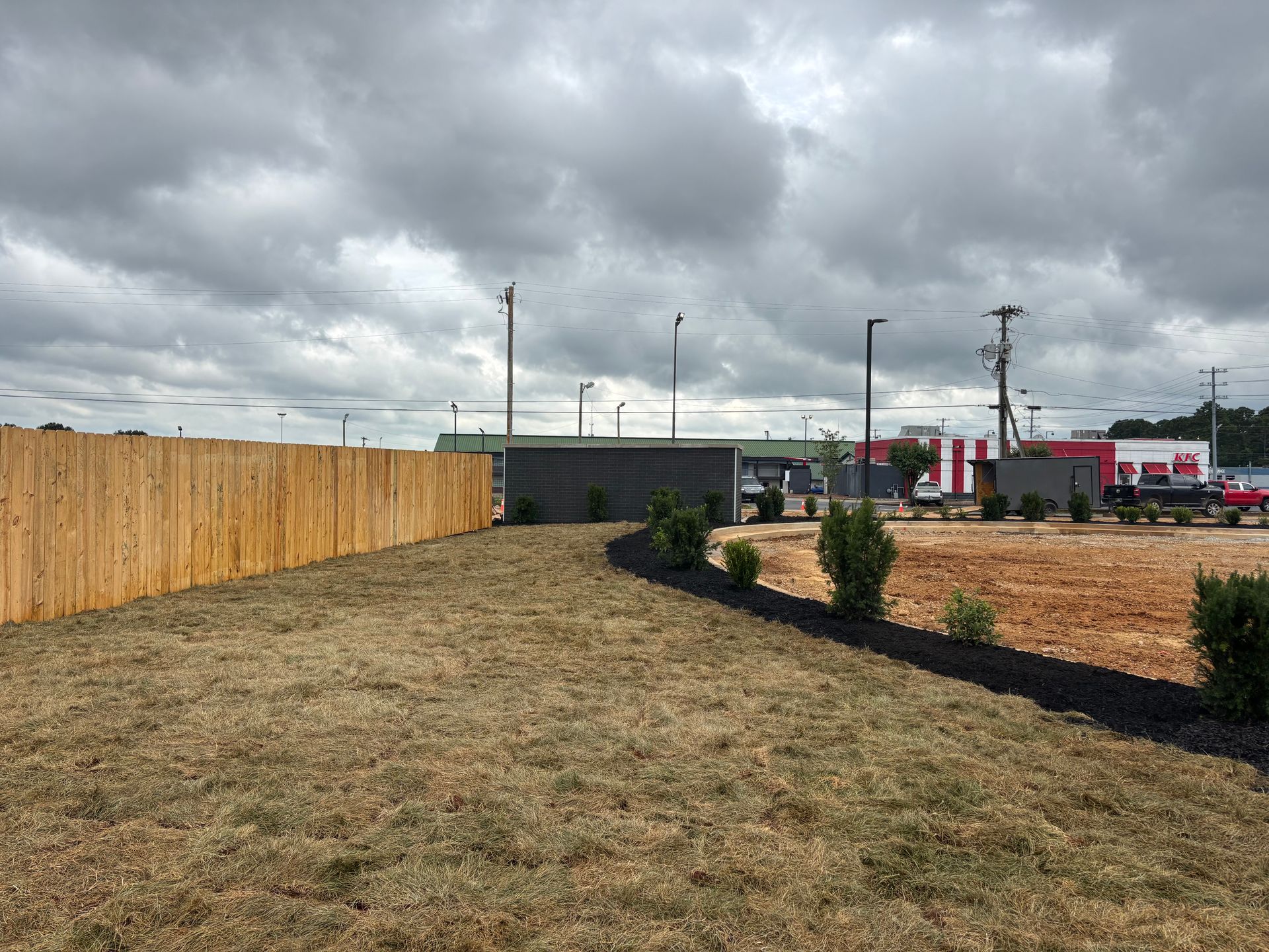 A wooden fence surrounds a grassy field with a building in the background.