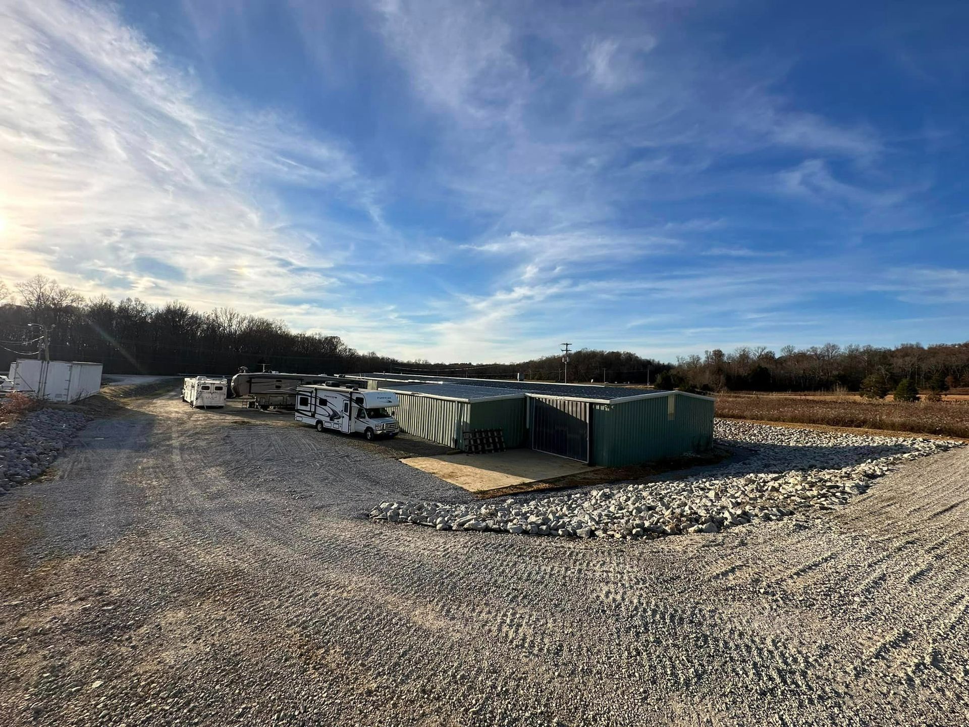 a lot of trucks are parked in a gravel lot .