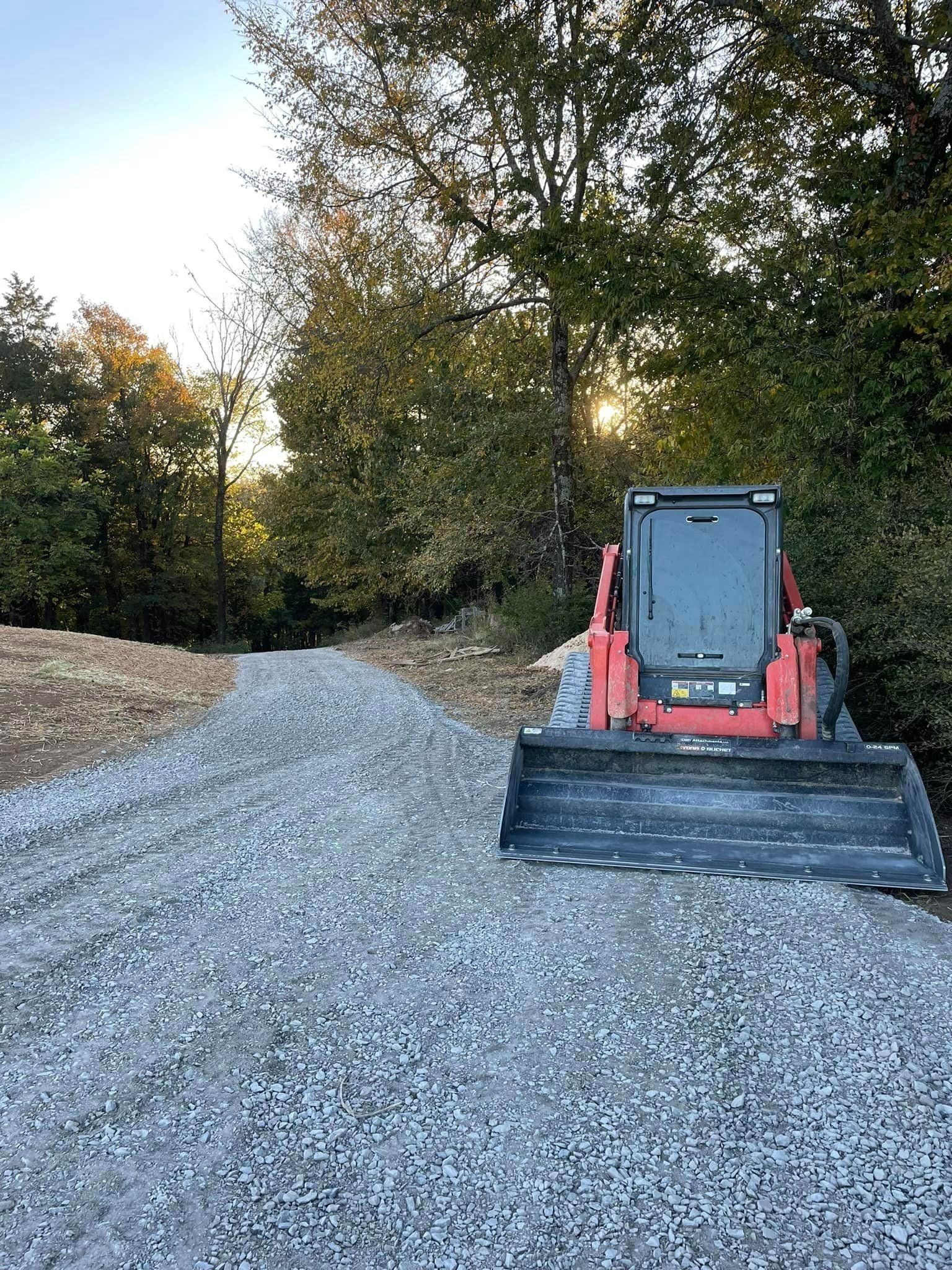 a bulldozer is parked on the side of a gravel road .