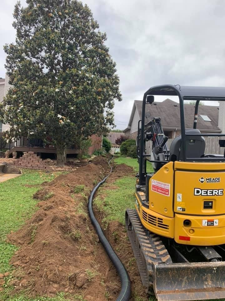 a yellow deere excavator is sitting in a yard next to a tree .