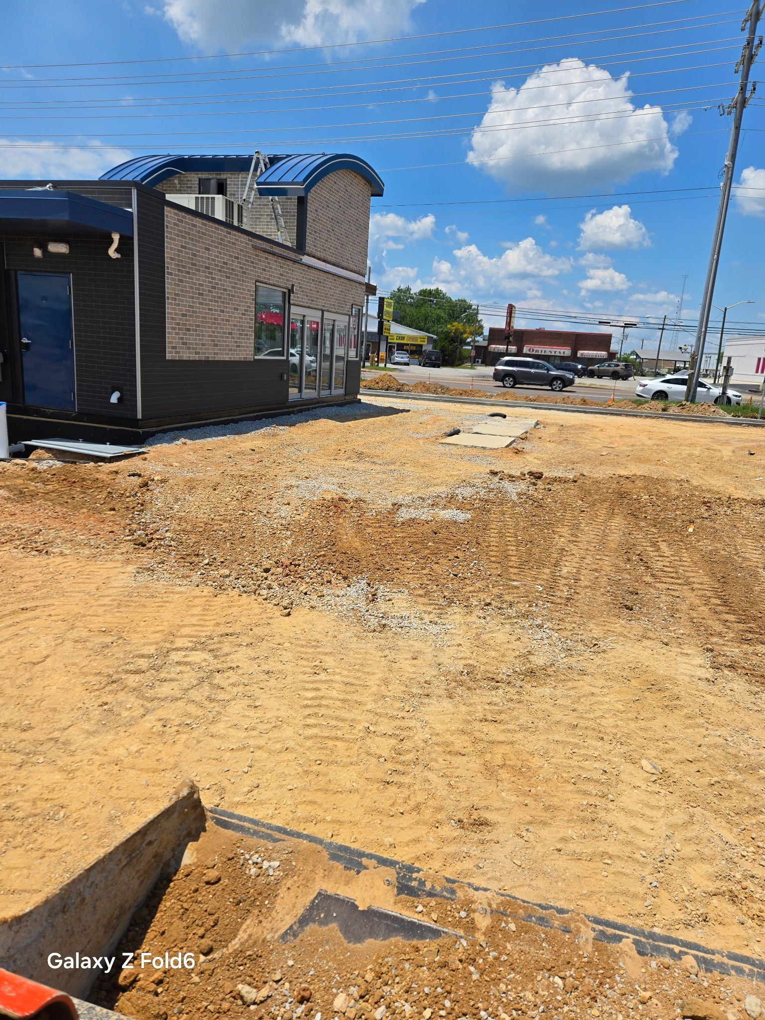 A construction site with a building in the background and a lot of dirt in the foreground.