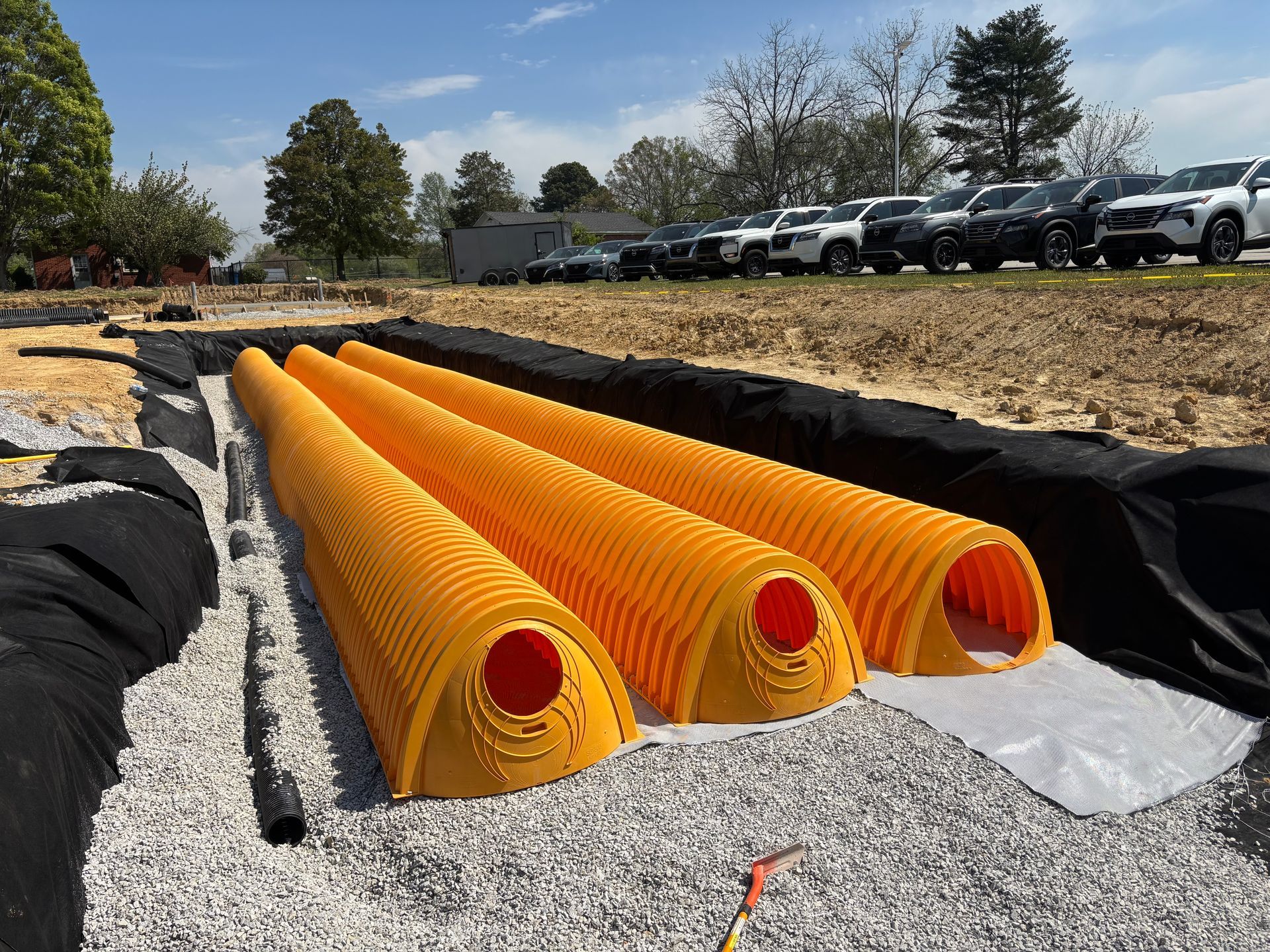 Three yellow pipes are sitting on top of a pile of gravel.