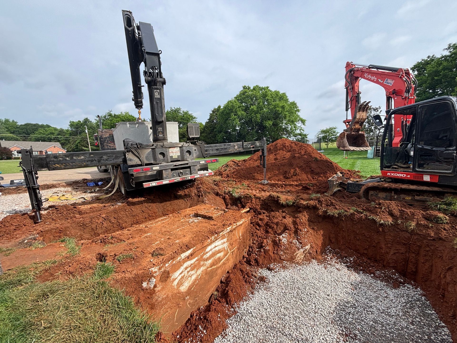 A truck with a crane attached to it is digging a hole in the ground.