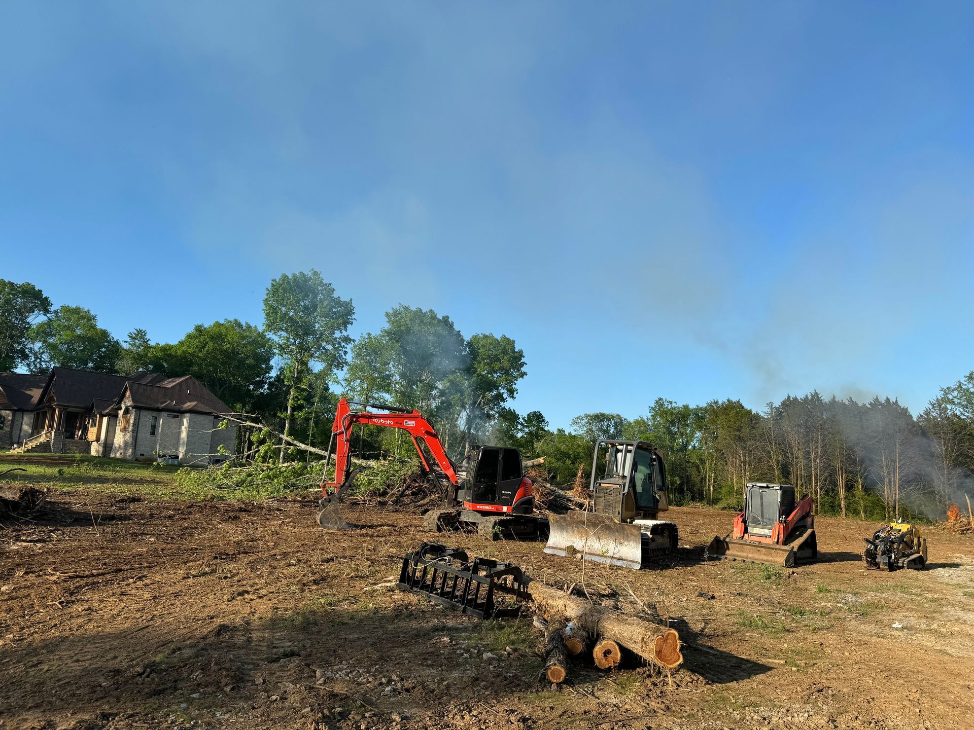 A group of construction vehicles are working on a dirt field.