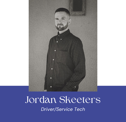 Jordan Skeeters, a Driver/Service Tech, poses for a headshot. He stands in front of a neutral backdrop, wearing a button-down shirt.