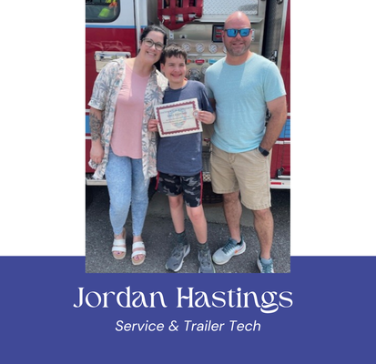 A family poses by a fire truck. A boy holds a certificate. Text says, 