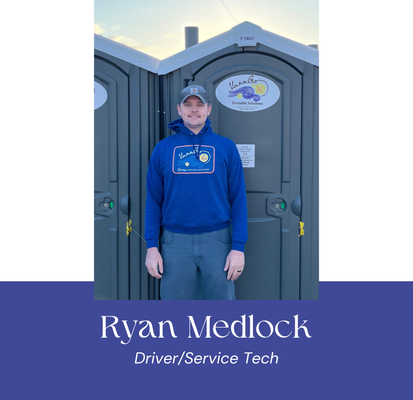 Man in blue sweatshirt standing in front of portable toilets. Text: 