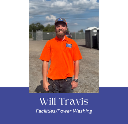 Man in orange shirt, baseball cap, stands outside near portable toilets. 