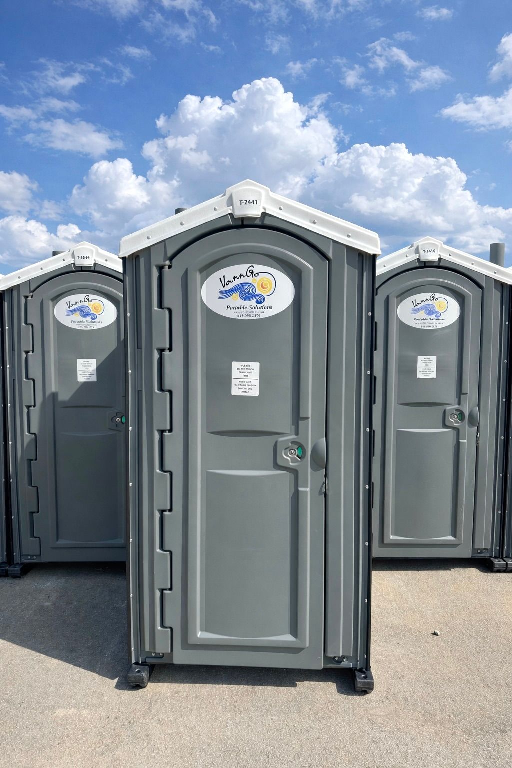 Two gray portable toilets with white roof trim.