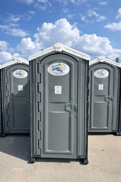 Two gray portable toilets with white roof trim.